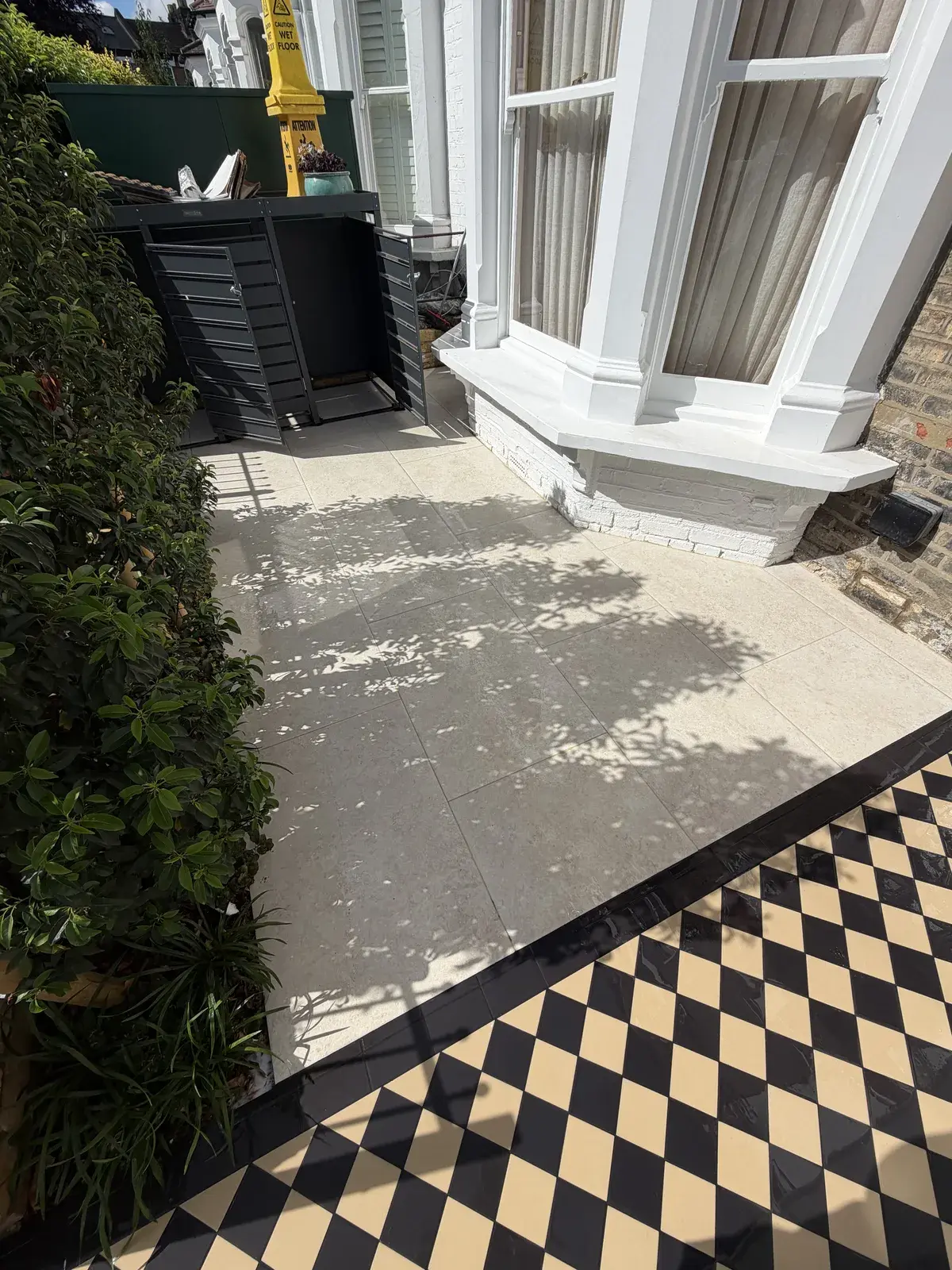 Black and white tiled Victorian path cleaned alongside a rendered bay