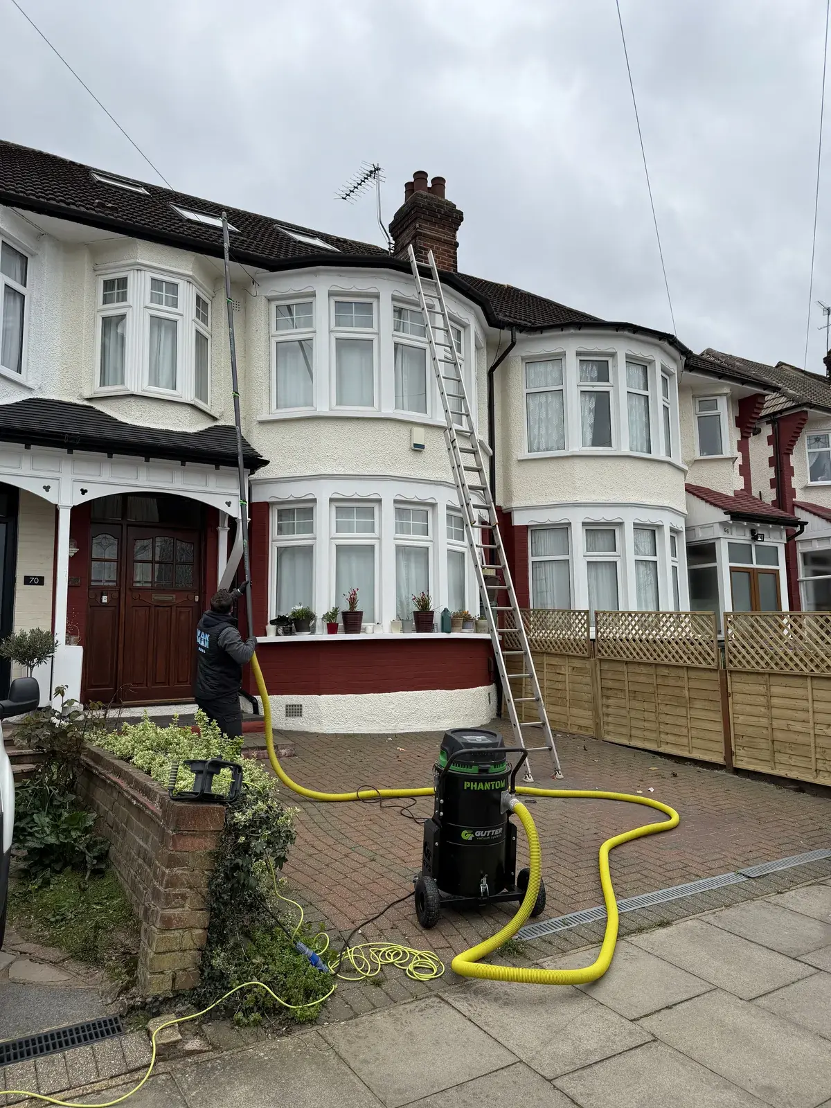 Gutter vacuum hose and ladder set up at the front of a North London semi