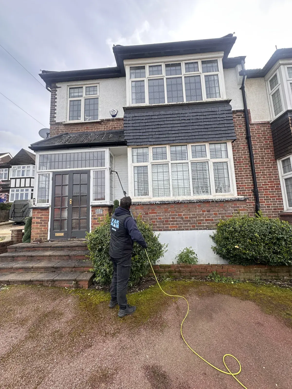 Vakman cleaning the upstairs windows of a 1930s semi with a water-fed pole